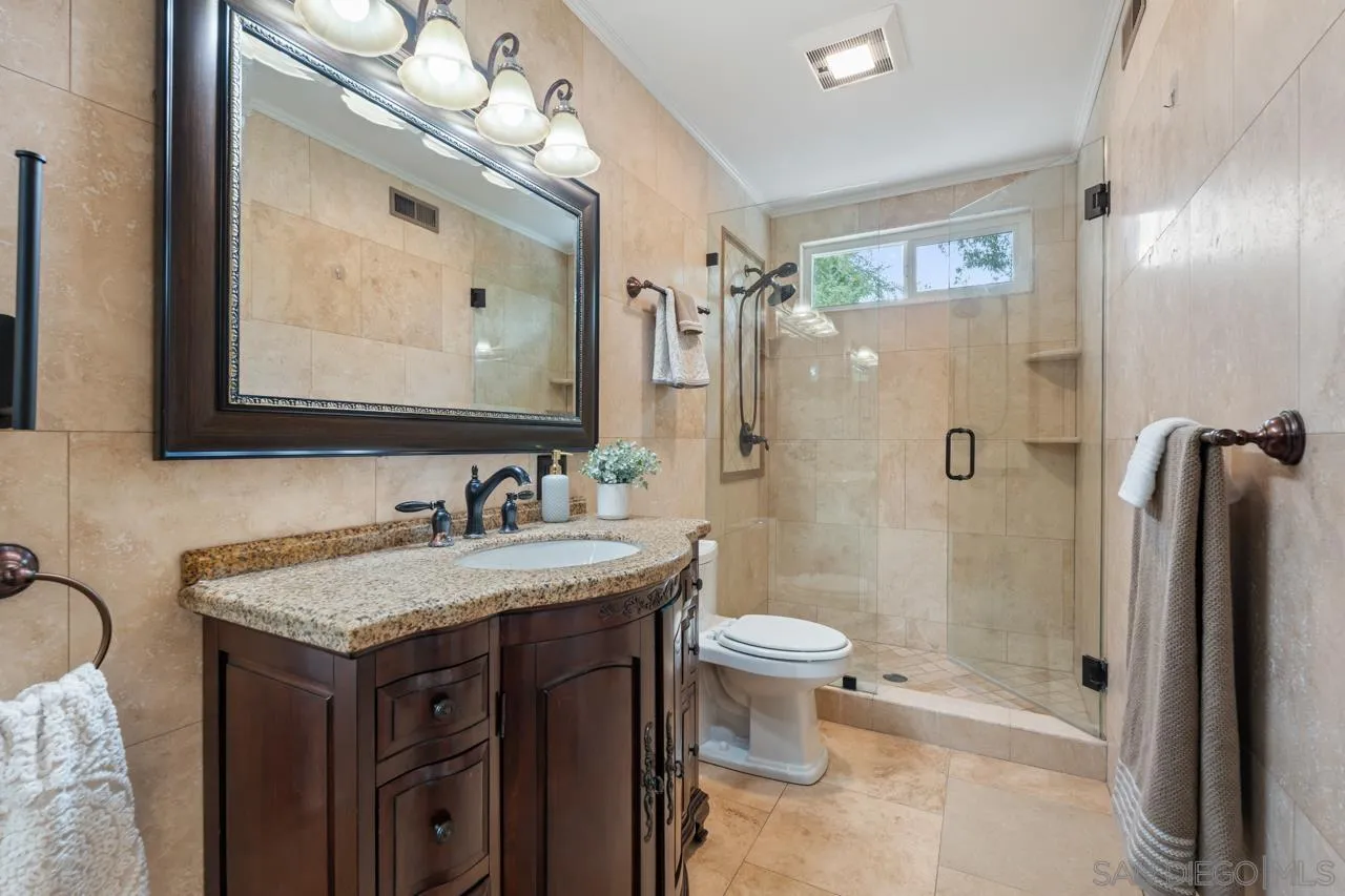 11837 La Colina Road San Diego, CA 92131 - Photo 18 of 35 a bathroom with a granite countertop sink toilet a large mirror a shower and a mirror