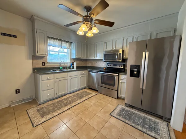 a kitchen with stainless steel appliances granite countertop a sink a stove a refrigerator cabinets and a window