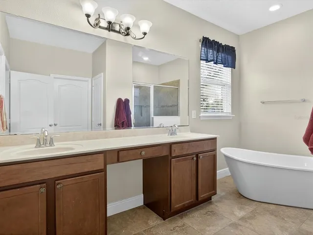 a spacious bathroom with a double vanity sink a large mirror and a bathtub