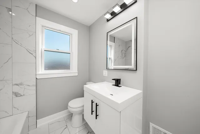 a bathroom with a toilet sink and mirror