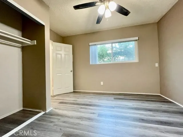 an empty room with wooden floor chandelier fan and windows
