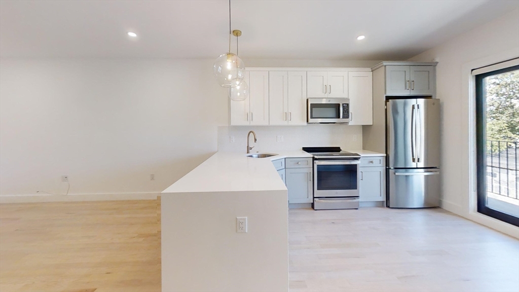 52 Withington Street, Unit 7 Boston, MA 02124 - Photo 4 of 32 a kitchen with stainless steel appliances a refrigerator and a stove top oven