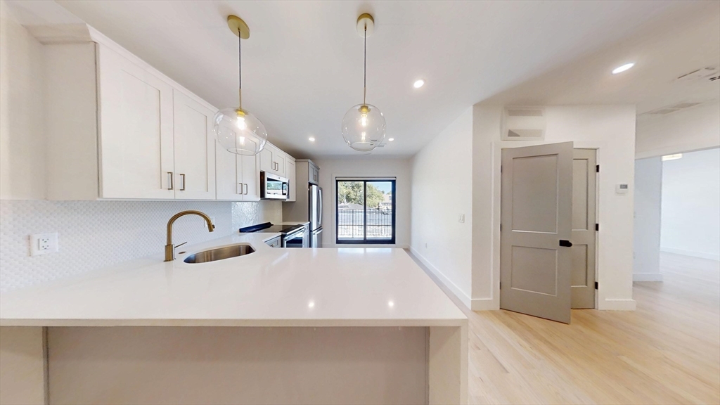 52 Withington Street, Unit 7 Boston, MA 02124 - Photo 5 of 32 a kitchen with kitchen island a sink and refrigerator