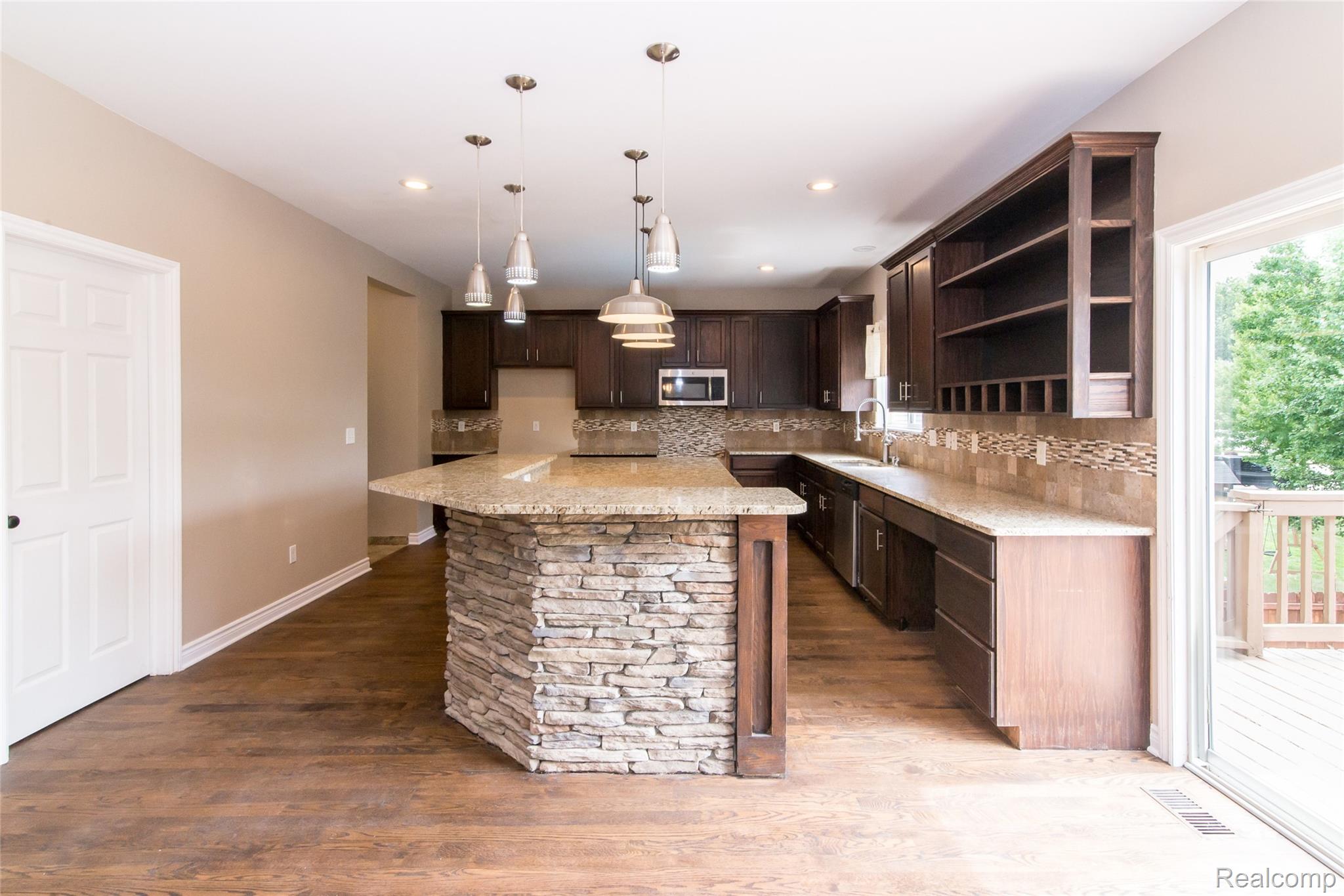 486 Sweet Briar Ridge Linden, MI 48451 - Photo 26 of 69 Kitchen with wood-finish flooring, dark wood cabinetry, and pendant lighting