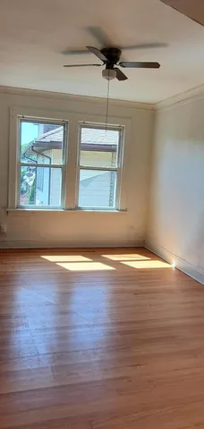 a view of empty room with wooden floor and fan
