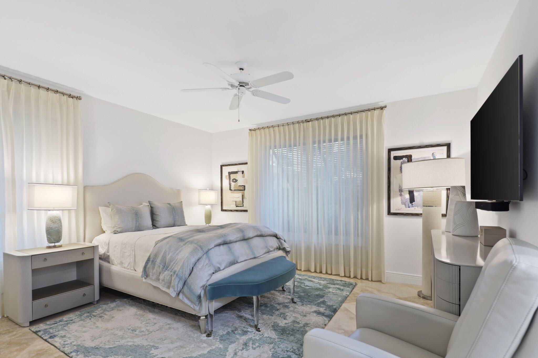 7400 Northeast Orchid Bay Drive Boca Raton, FL 33487 - Photo 42 of 63 a bedroom with a bed a couch and a flat tv screen on the dresser