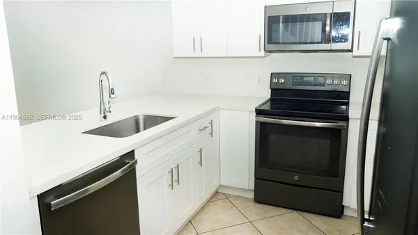 a kitchen with granite countertop white cabinets and stainless steel appliances