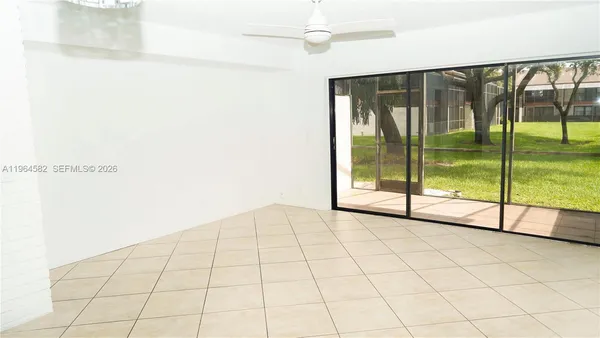 a view of an empty room and chandelier fan