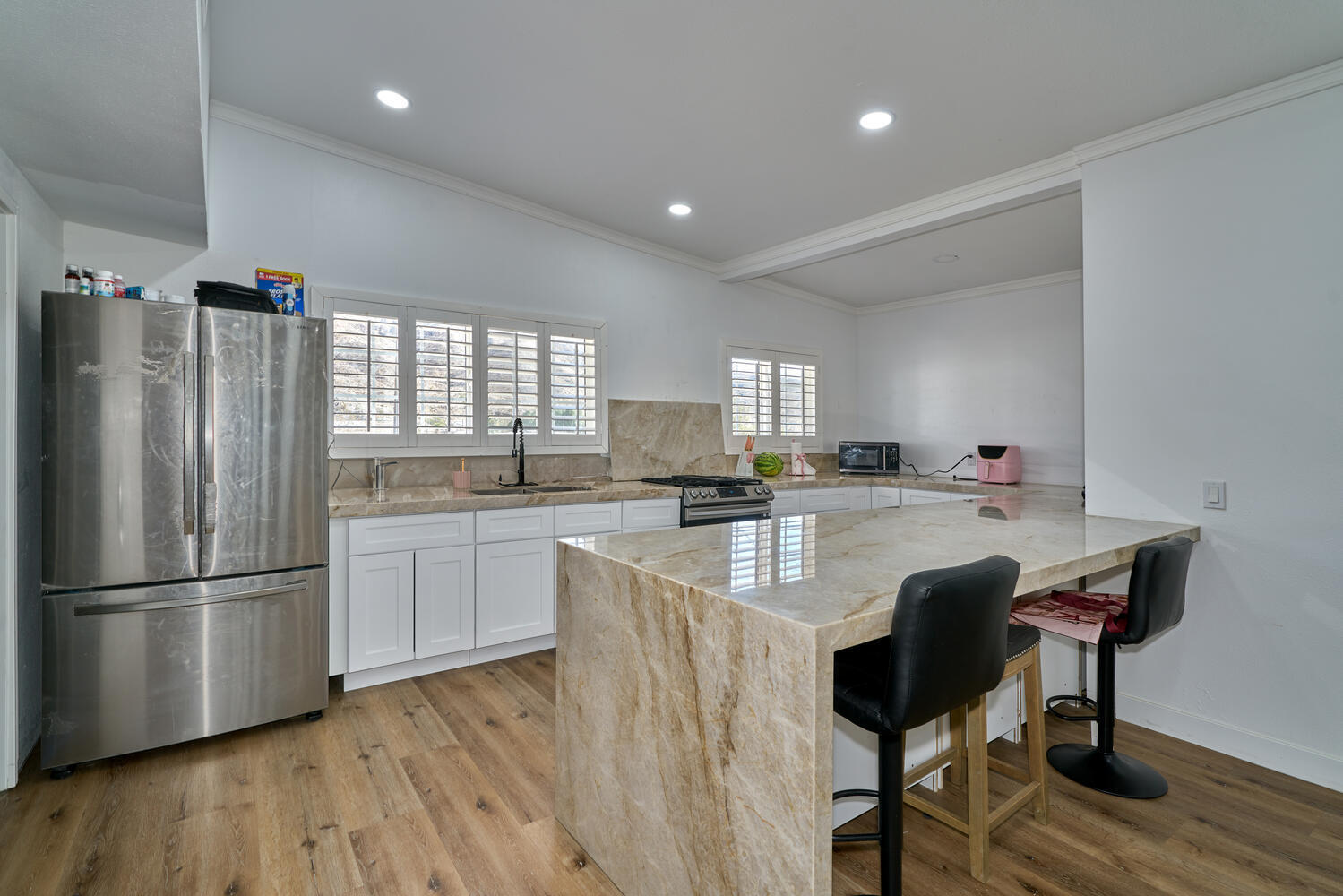 73300 Paradise Avenue Desert Hot Springs, CA 92241 - Photo 27 of 44 a kitchen with stainless steel appliances granite countertop a refrigerator a sink dishwasher a stove a dining table and chairs with wooden floor