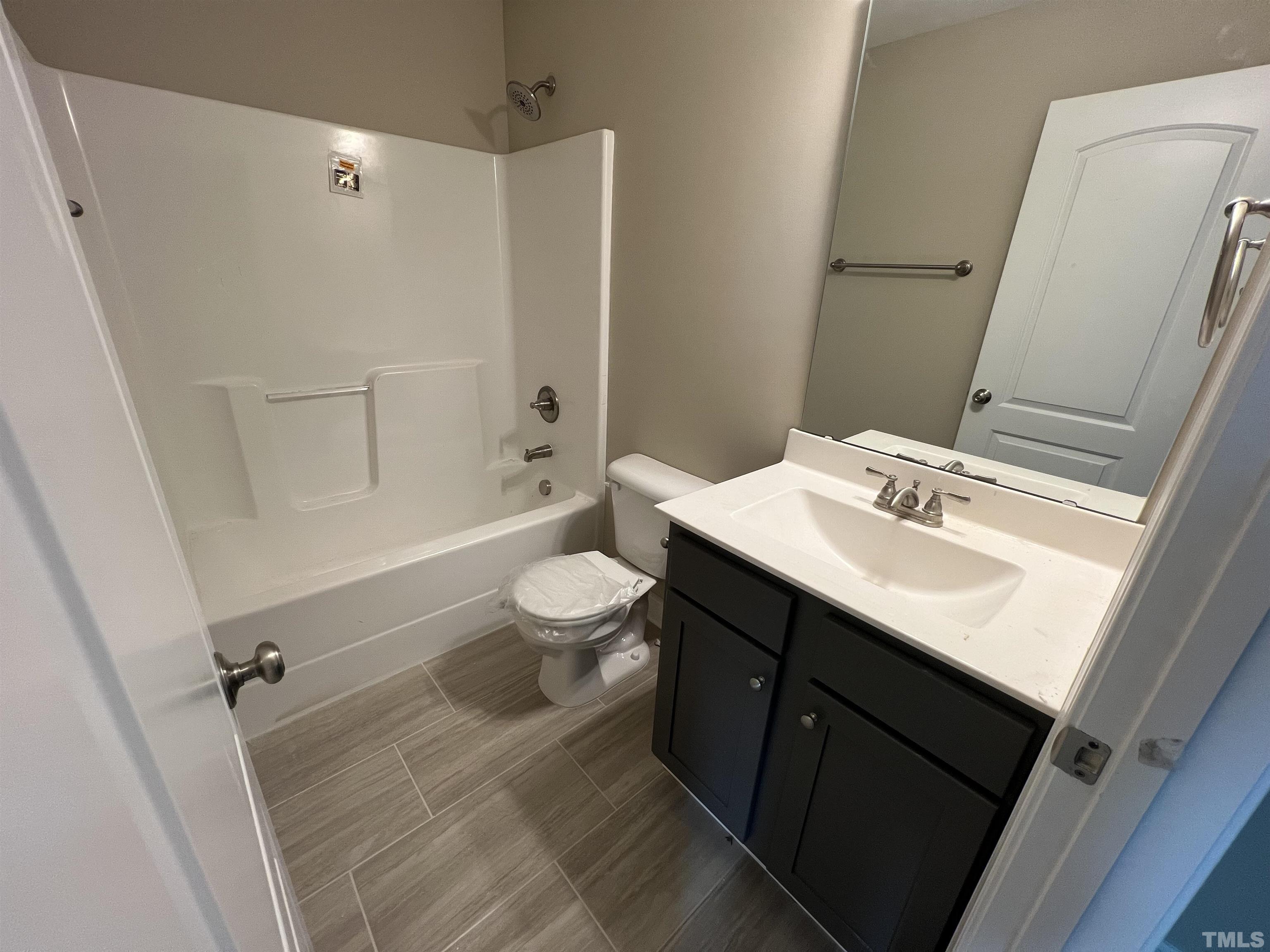 59 Cricket Hill Way Benson, NC 27504 - Photo 23 of 28 a bathroom with a sink a toilet a mirror and shower