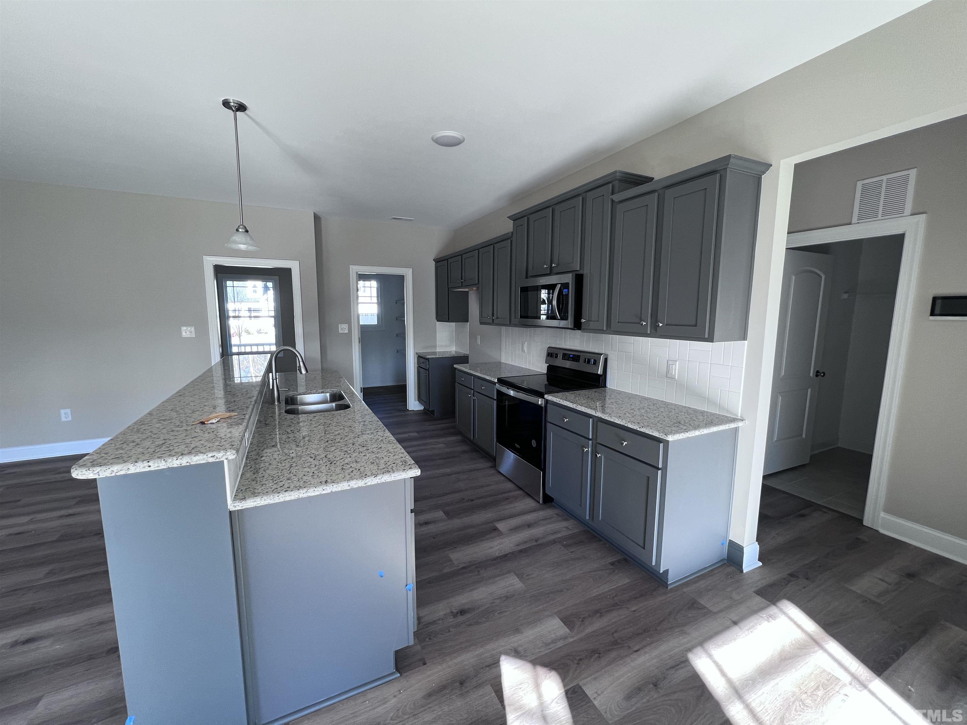 59 Cricket Hill Way Benson, NC 27504 - Photo 10 of 28 a kitchen with stainless steel appliances granite countertop a sink stove and wooden floor