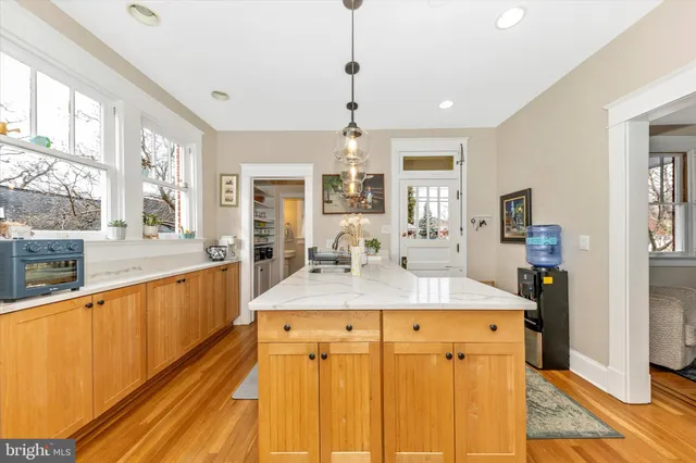 a view of a kitchen with kitchen island granite countertop a large window cabinets and stainless steel appliances