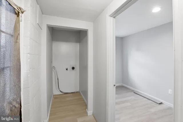 a view of a hallway with wooden floor and a bathroom