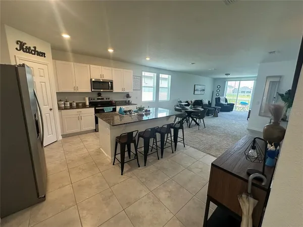 a kitchen with stainless steel appliances granite countertop a stove top oven a sink a dining table and chairs