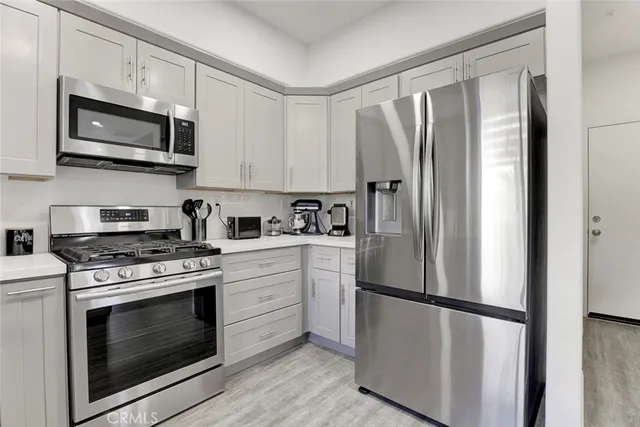 a kitchen with white cabinets and stainless steel appliances