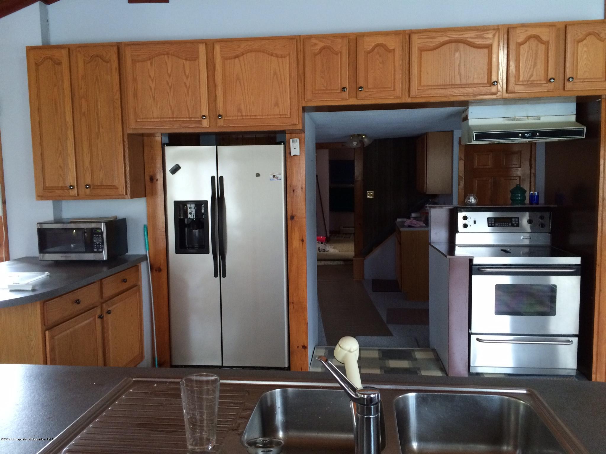 154 Transue Road Laceyville, PA 18623 - Photo 6 of 28 a kitchen with kitchen island granite countertop wooden cabinets and a refrigerator