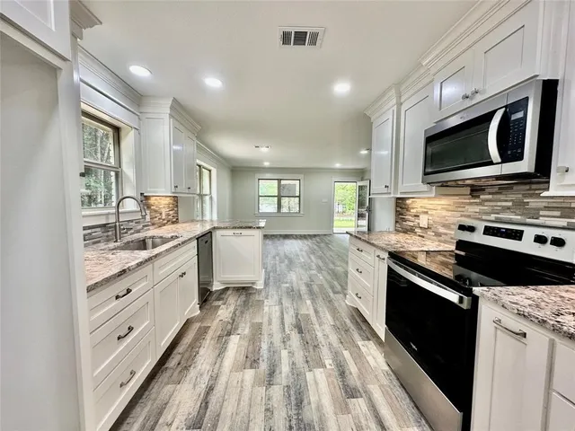 a view of a room with kitchen island stainless steel appliances wooden floor and windows