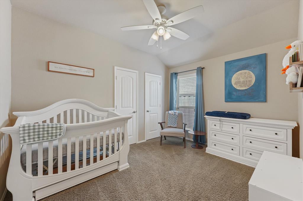 409 Harding Lane Lavon, TX 75166 - Photo 6 of 34 Carpeted room featuring a vaulted ceiling with a ceiling fan, two paneled doors, and a window with blinds and drapes