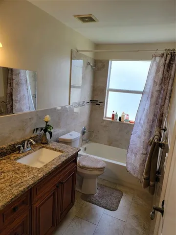 a bathroom with a granite countertop sink a toilet a mirror and bathtub