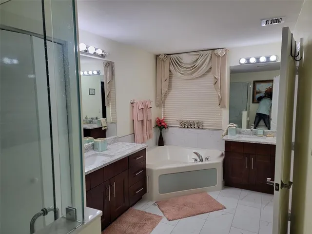 a spacious bathroom with a tub sink and mirror