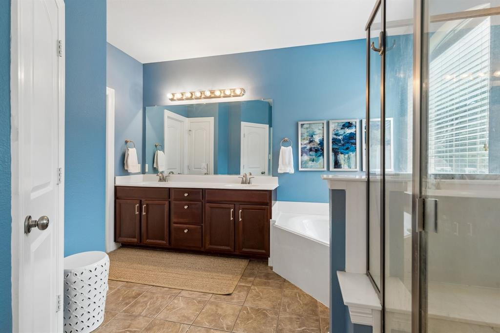 960 Remuda Road Frisco, TX 75033 - Photo 17 of 39 Spacious bath featuring a dual vanity with wood cabinetry, a large soaking tub, and a separate glass-enclosed shower
