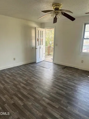 an empty room with wooden floor fan and windows