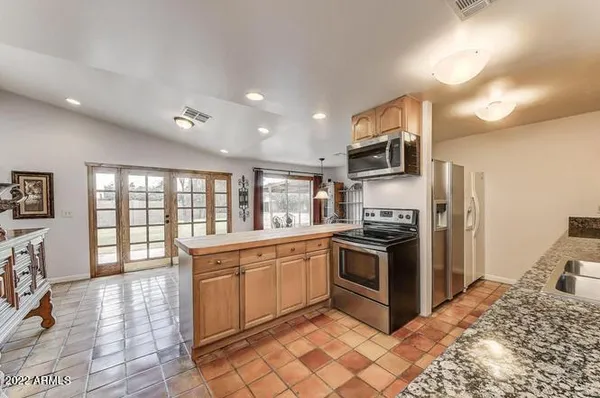a kitchen with stainless steel appliances granite countertop a stove top oven a sink dishwasher a dining table and chairs with wooden floor