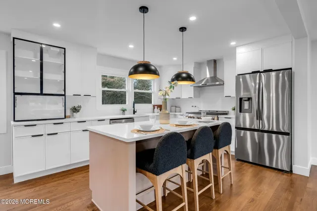 a kitchen with stainless steel appliances granite countertop a sink a stove a refrigerator and island with wooden floor