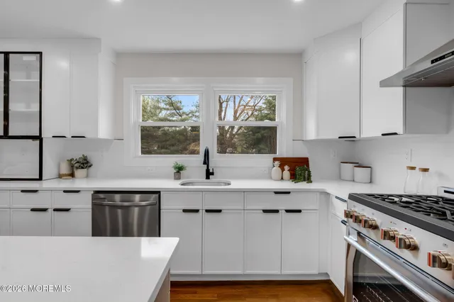 a kitchen with a stove a sink a window and cabinets