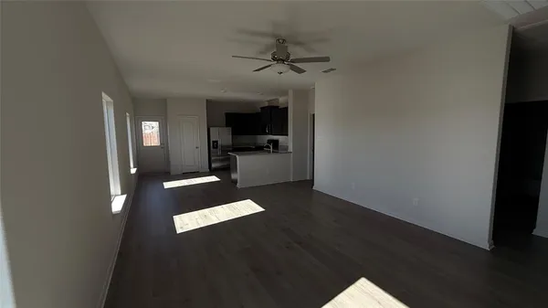a living room with stainless steel appliances wooden floors and view kitchen