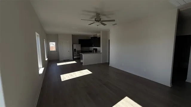 a living room with stainless steel appliances wooden floors and view kitchen