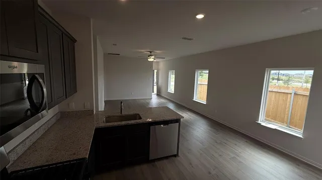 a kitchen with stainless steel appliances granite countertop a refrigerator a sink dishwasher and a stove with wooden floor