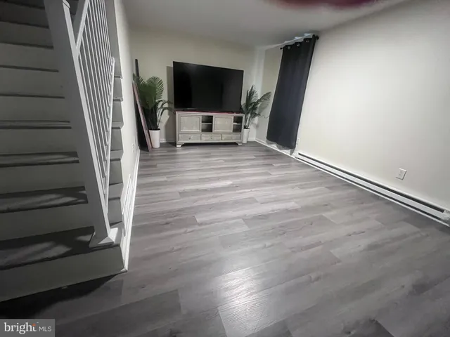a view of a livingroom with wooden floor and a flat screen tv