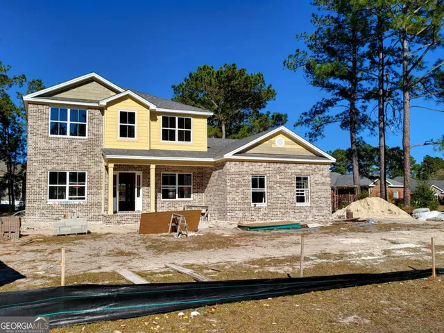 a view of a white house with a yard tree and wooden fence