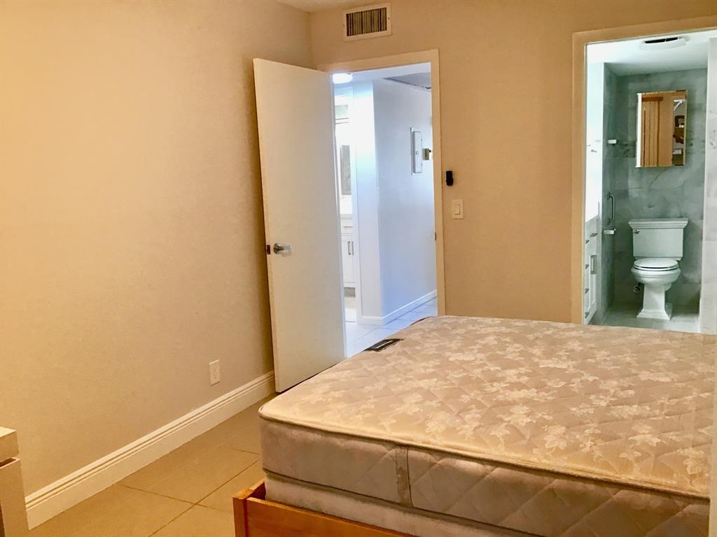 1004 Newcastle A, Unit 1004 Boca Raton, FL 33434 - Photo 18 of 39 a bedroom with a bed and painting on the wall