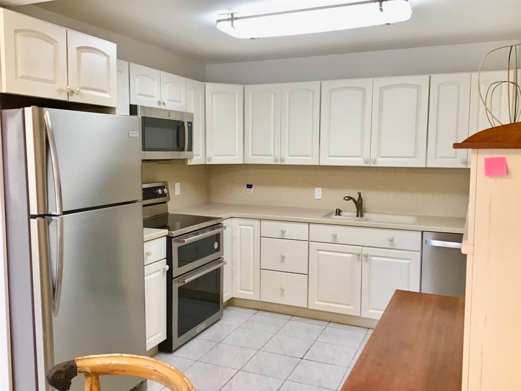 1004 Newcastle A, Unit 1004 Boca Raton, FL 33434 - Photo 2 of 39 a kitchen with white cabinets stainless steel appliances and a sink