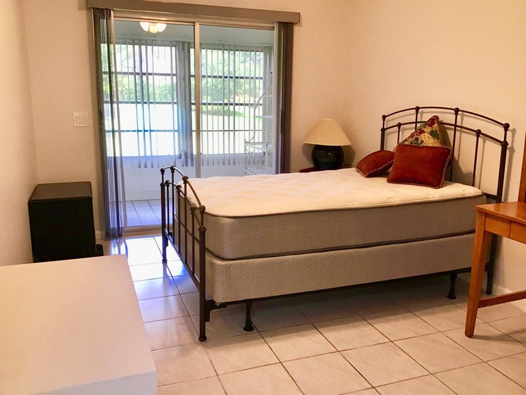 1004 Newcastle A, Unit 1004 Boca Raton, FL 33434 - Photo 26 of 39 a bed sitting in a bedroom next to a window