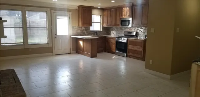 a open kitchen with stainless steel appliances granite countertop a stove a sink and a microwave