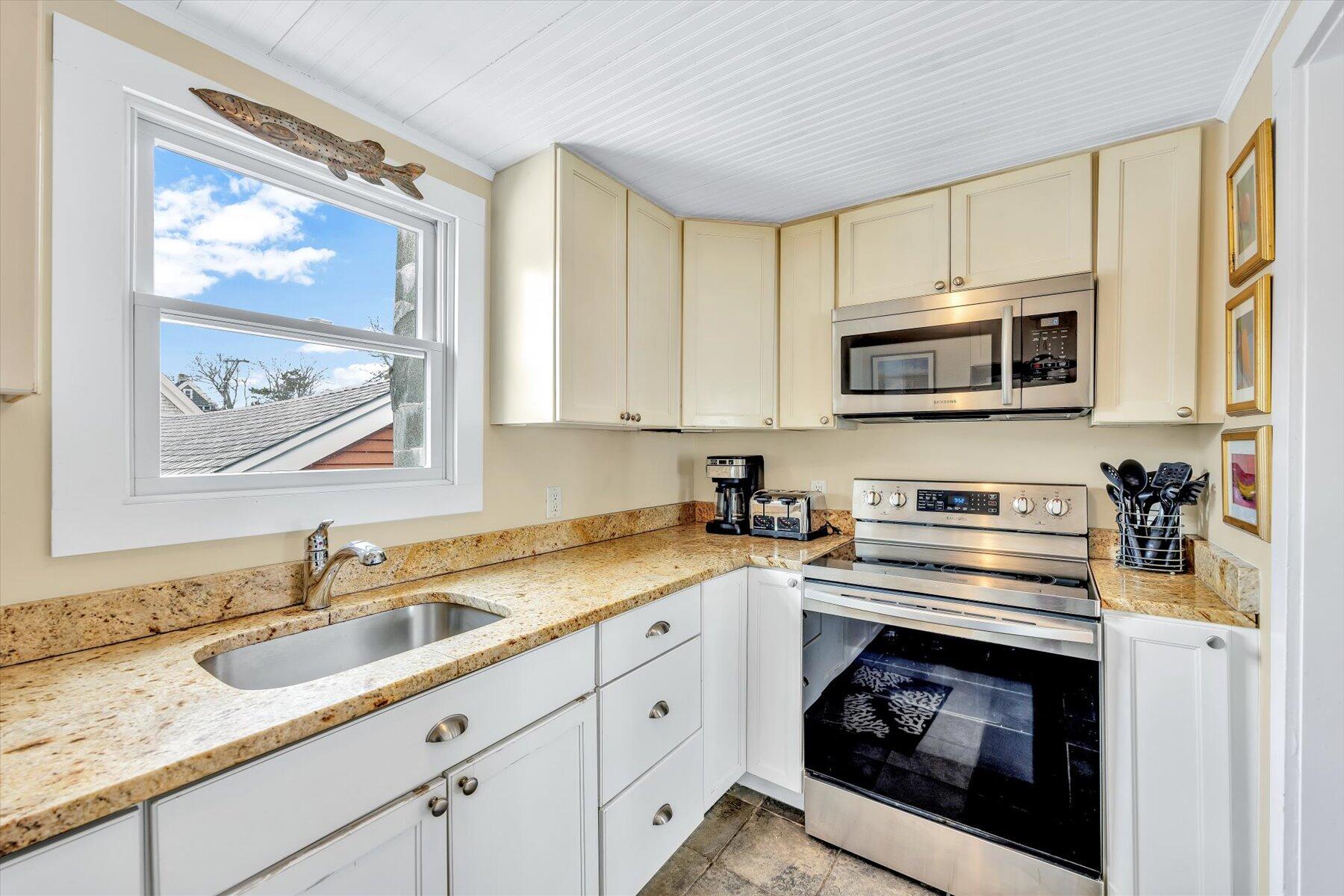 15 Cottage Street, Unit 2 Provincetown, MA 02657 - Photo 18 of 27 a kitchen with stainless steel appliances granite countertop a stove microwave and sink