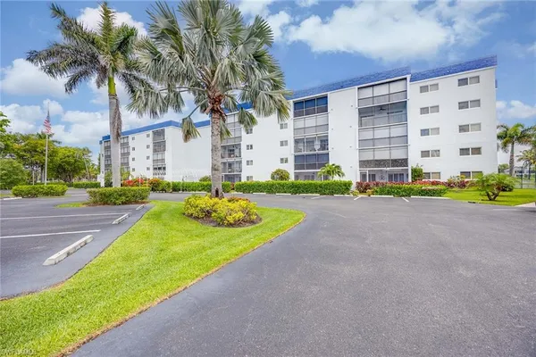 a view of a building with a yard and palm trees