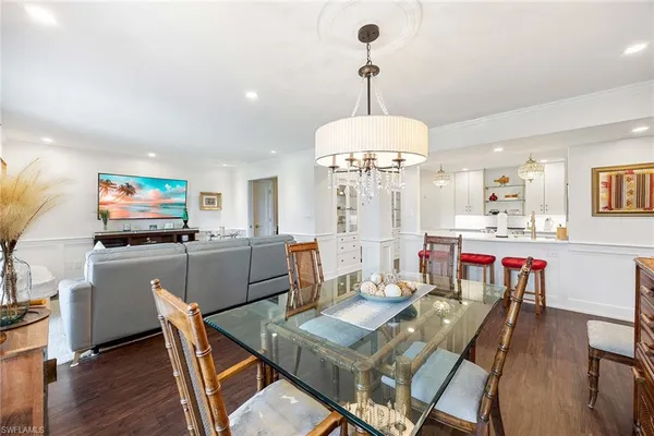 a view of a dining room and livingroom with furniture wooden floor a chandelier