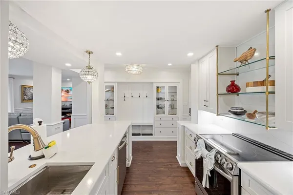 a large kitchen with stainless steel appliances kitchen island a large counter top a stove a chimney a sink and cabinets