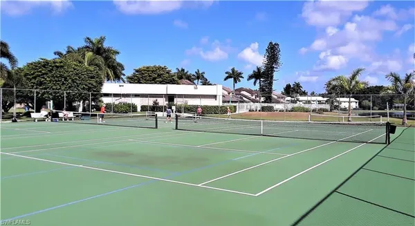 a view of a tennis ground with large trees