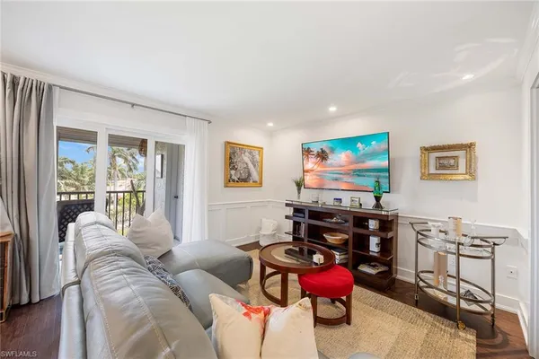a living room with furniture a flat screen tv and a floor to ceiling window
