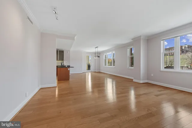a view of an empty room with window and wooden floor