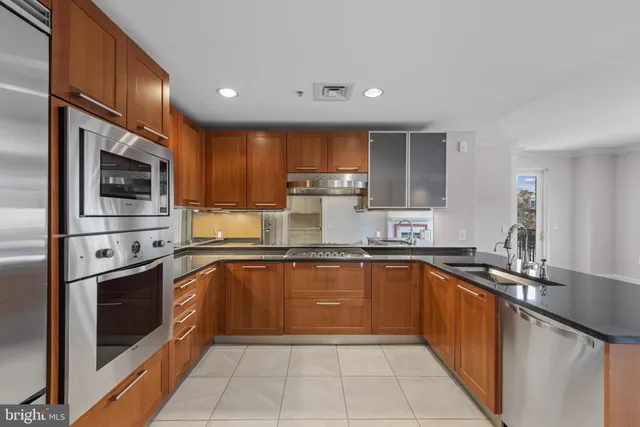 a kitchen with stainless steel appliances granite countertop a sink refrigerator and cabinets