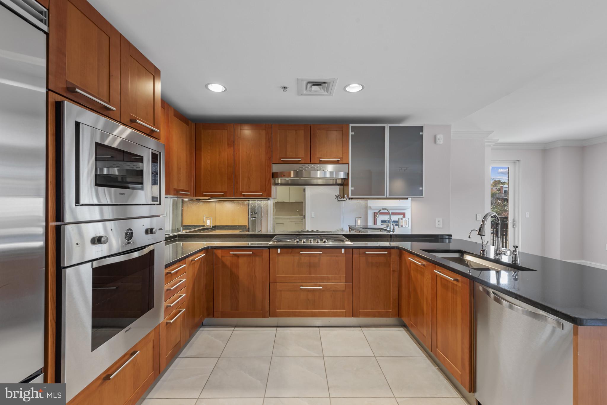 801 Key Highway, Unit 364 Baltimore, MD 21230 - Photo 7 of 54 a kitchen with stainless steel appliances granite countertop a sink and stove top oven with wooden cabinets