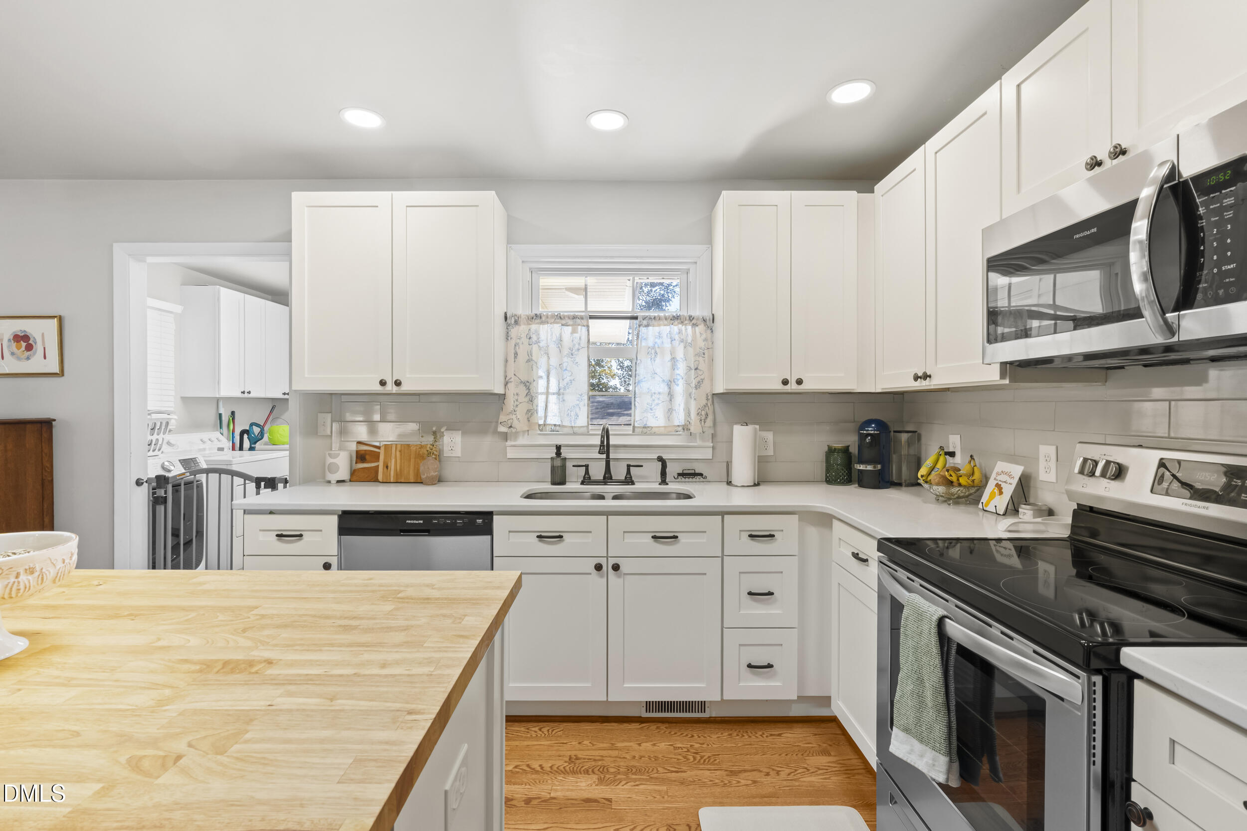 3032 Rosinburg Road Zebulon, NC 27597 - Photo 12 of 28 a large kitchen with stainless steel appliances granite countertop a stove a sink dishwasher and white cabinets with wooden floor