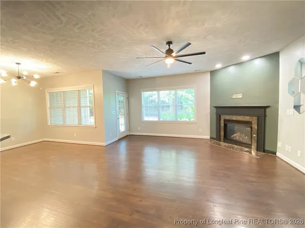 an empty room with wooden floor fireplace and windows