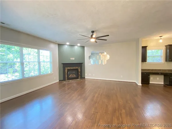 an empty room with wooden floor fireplace and windows